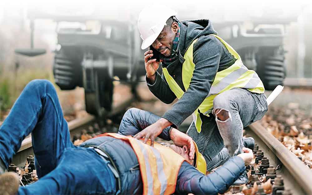Construction worker on the ground injured while a coworker in a hard hat calls for help