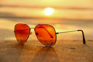 Sunglasses resting on the sand at the beach at sunset